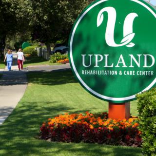 A sign for Upland Rehabilitation & Care Center surrounded by well-maintained landscaping.