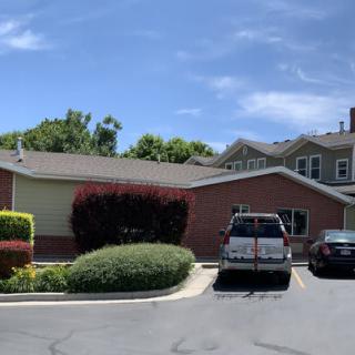 A residential building with cars parked in the driveway under a clear blue sky.
