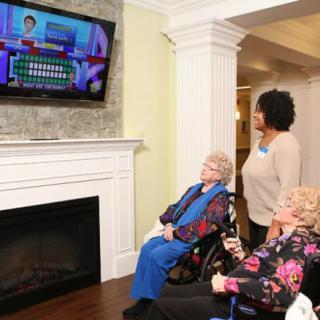 A group of elderly individuals watching a game show on television in a cozy living area.