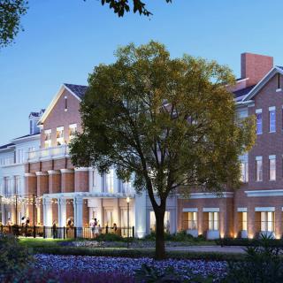 A beautifully lit building with a garden and tree in the evening.