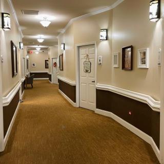 A well-lit hallway with framed pictures on the walls and a carpeted floor.