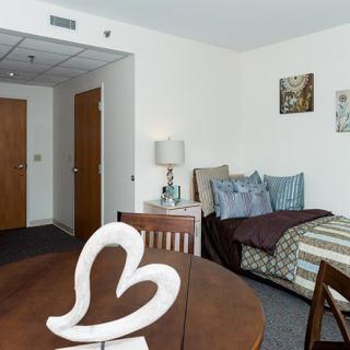 A cozy studio apartment with a neatly arranged bed and dining area.