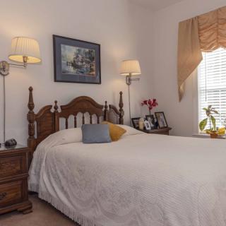 A cozy bedroom with a wooden bed frame, soft white bedding, and elegant lamps alongside decorative elements.