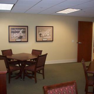 A well-designed office meeting area with a table, several chairs, and framed artwork on the walls.