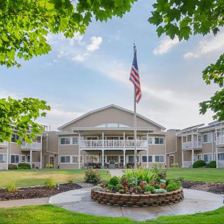A residential building with well-maintained landscaping and an American flag in the foreground.