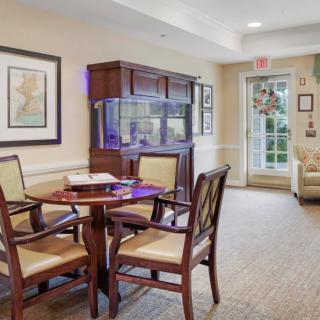 A cozy interior dining area with a round table, chairs, and a fish tank.