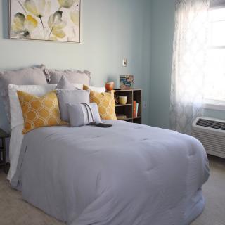 A cozy bedroom with soft lighting and stylish decor, featuring a neatly made bed with decorative pillows.
