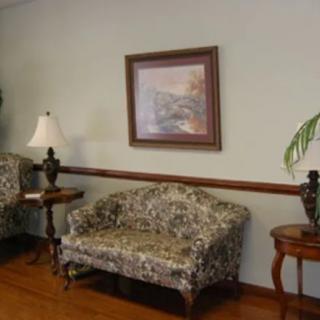 A cozy living room setup with a patterned sofa, two lamps on side tables, and a framed painting on the wall.