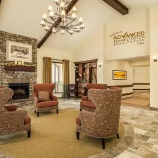 A cozy lobby interior featuring a seating area with armchairs, a fireplace, and a chandelier.