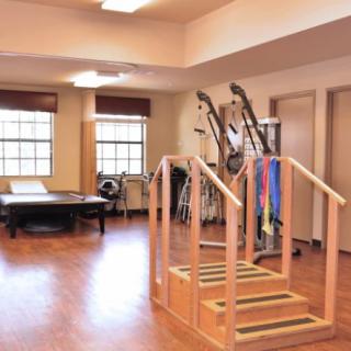 A spacious rehabilitation room equipped with exercise equipment and wooden stairs for therapy exercises.