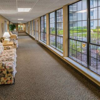 A long indoor corridor with large windows and comfortable seating.