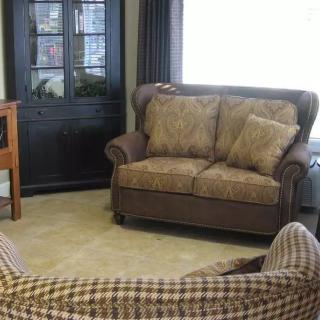 A cozy living room with a sofa, armchair, and cabinet.