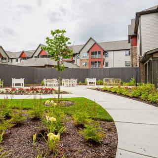 A landscaped garden with a curved pathway surrounded by buildings.