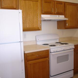 A kitchen with wooden cabinets, a white refrigerator, and a stove.