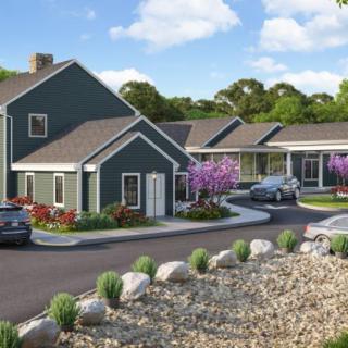 A modern residential building with a landscaped garden and driveway.