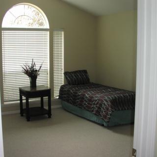 A minimalist bedroom with a single bed, decorative table, and a window with blinds.