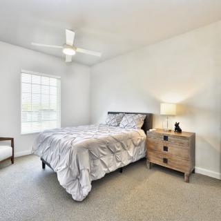 A simple, modern bedroom with a bed, nightstand, and ceiling fan.