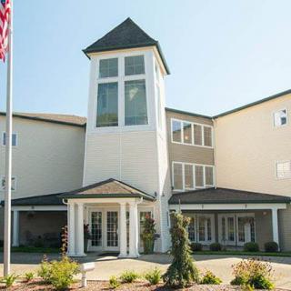 A modern multi-story building with a prominent entrance and flagpole.