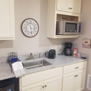 A small kitchen area with a countertop, sink, microwave, and coffee maker.