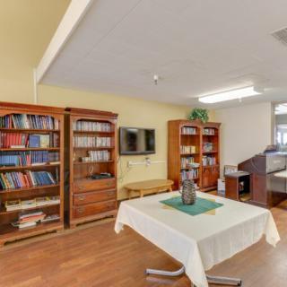 A cozy living room with bookcases, a television, and a table covered with a tablecloth.