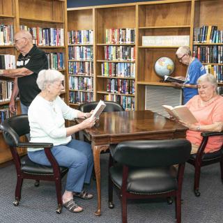 Seniors enjoying reading in a library setting.