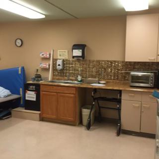 A hospital or clinic room with a bed, sink, and microwave.