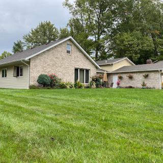 A cozy single-story house with a well-maintained lawn and surrounding greenery.