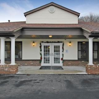 A front view of a building entrance with columns and double glass doors.