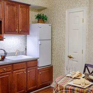 A cozy kitchen with wooden cabinets, a dining table, and appliances.