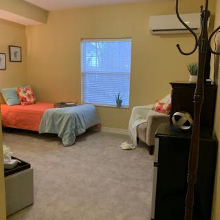 A cozy bedroom with a neatly made bed, window, and various furnishings.