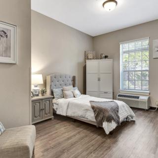 A cozy and modern bedroom with neutral tones, featuring a bed, wardrobe, and wooden flooring.