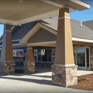 A modern building entrance with stone pillars and a peaked roof.
