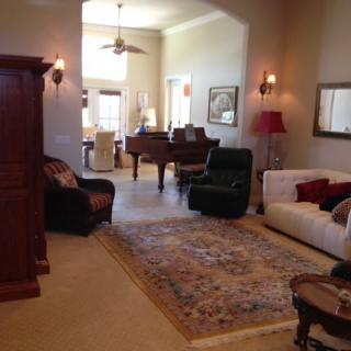 A cozy living room with traditional decor, featuring a sofa, armchair, piano, and a patterned carpet.