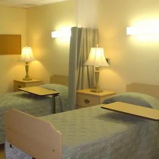 A hospital room with two beds and bedside lamps.
