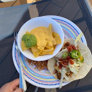 A delicious spread featuring tacos with toppings and a side of nachos with guacamole.