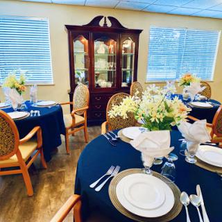 An elegantly arranged dining room featuring tables with blue tablecloths and beautiful floral centerpieces.