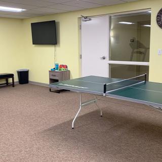 A recreational room featuring a ping pong table and a wall-mounted television.