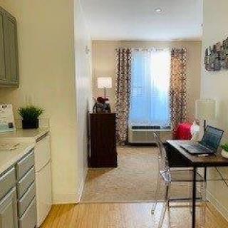 A cozy studio apartment with a simple desk setup and natural light.