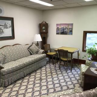 A cozy living room with a vintage sofa, patterned carpet, and a grandfather clock.