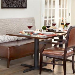 A cozy restaurant setting with a neatly set dining table, featuring red wine glasses and comfortable seating.