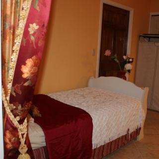 A cozy bedroom with a single bed, floral curtains, and warm lighting.