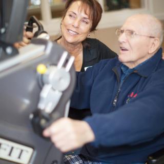 An elderly man exercising with the assistance of a trainer.