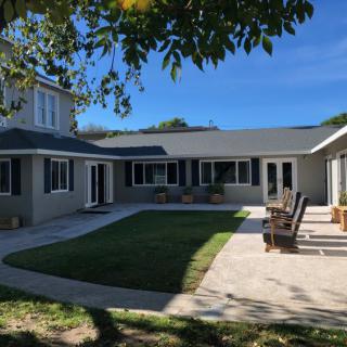 A spacious residential house with a large yard and patio under a clear blue sky.