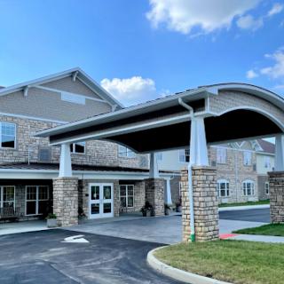 A welcoming entrance to a modern residential building with stone accents and a canopy.