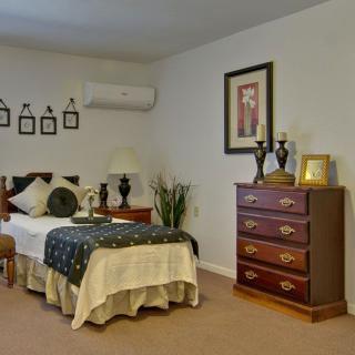 A cozy bedroom with a single bed, dresser, and decorative items on the walls.