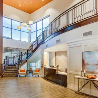A modern lobby with a grand staircase and reception area.