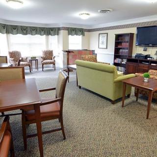 A cozy living room with chairs, tables, a sofa, and a television.
