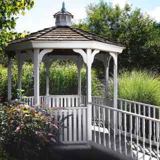 A charming wooden gazebo in a lush garden setting.