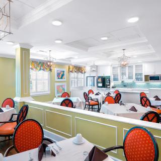 A stylish and modern dining area featuring vibrant red chairs and a bright, open kitchen space.