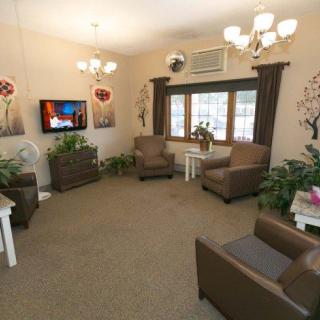 A cozy living room with comfortable chairs, indoor plants, and a television.